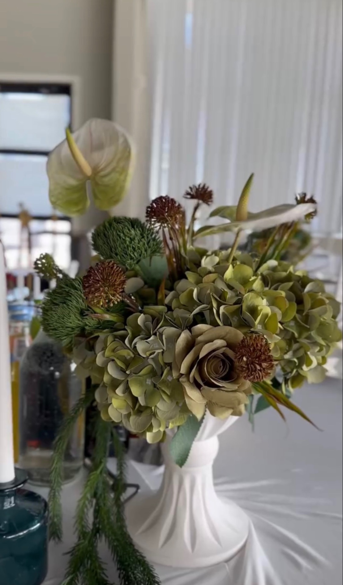 Grön blomsterkomposition i vit vas
