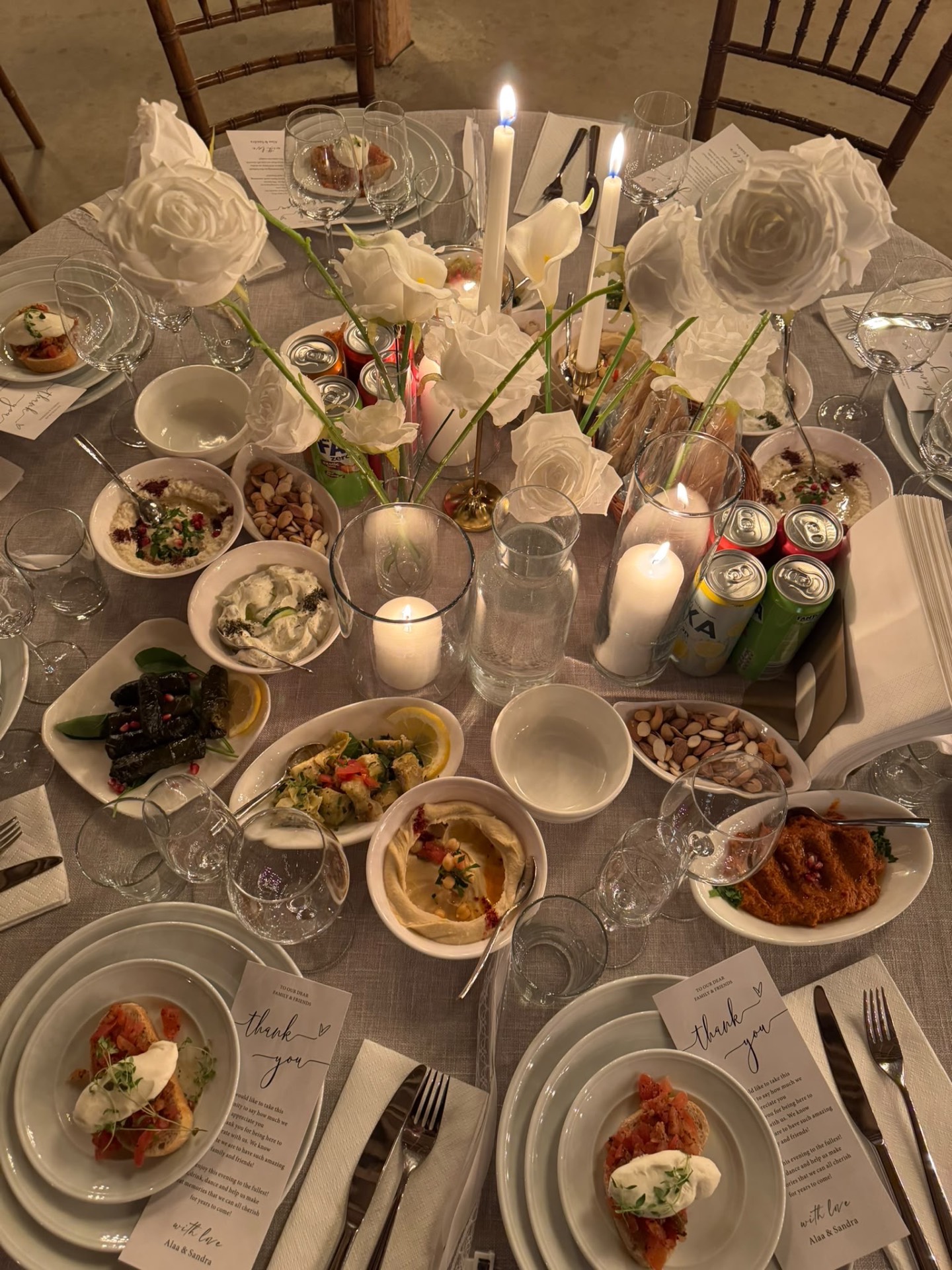 Klätt dukat middagsbord med blommor, ljus och mezze
