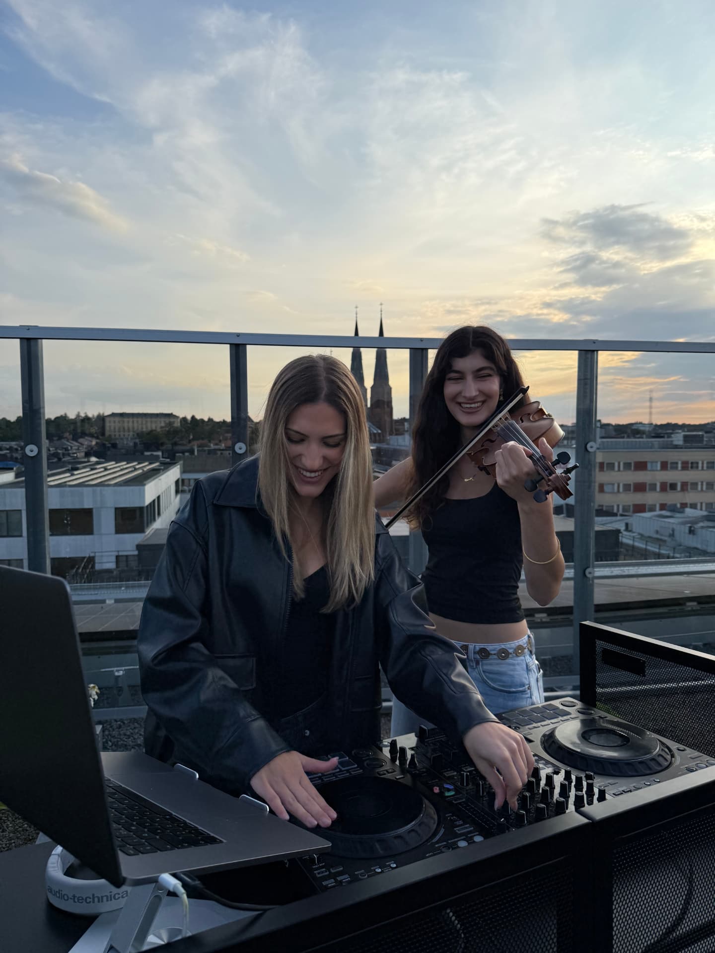 DJ och violinist på takterrass i solnedgången