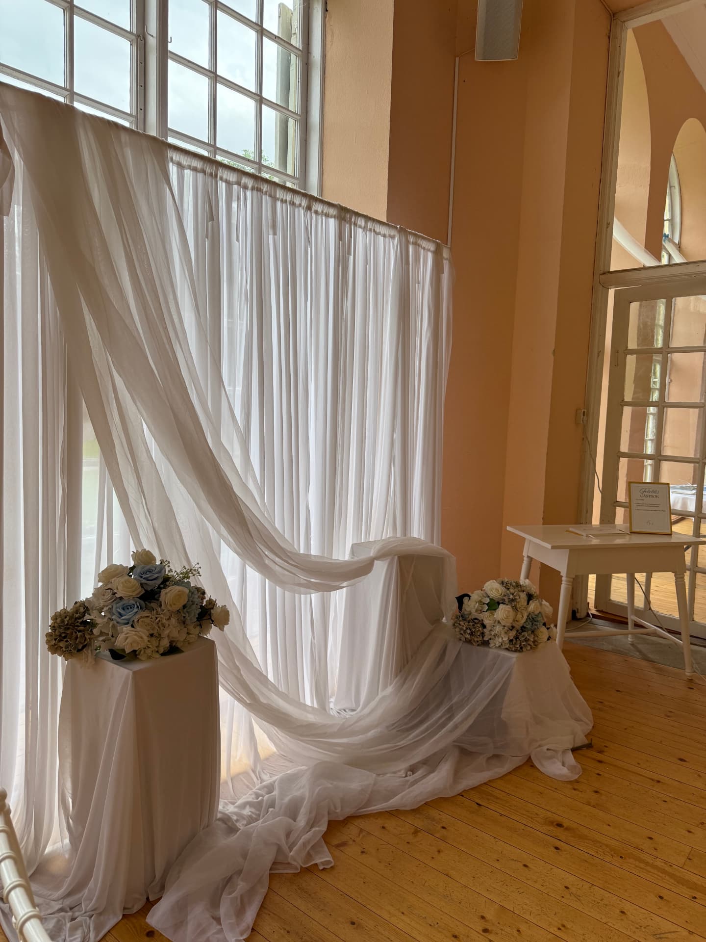 Vitt draperi och blomsterarrangemang i festlokal