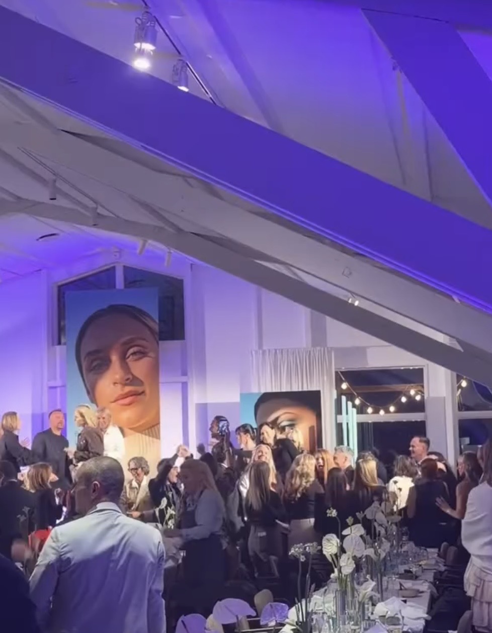 Mingelande gäster vid dukade långbord med stora porträttbilder på väggarna