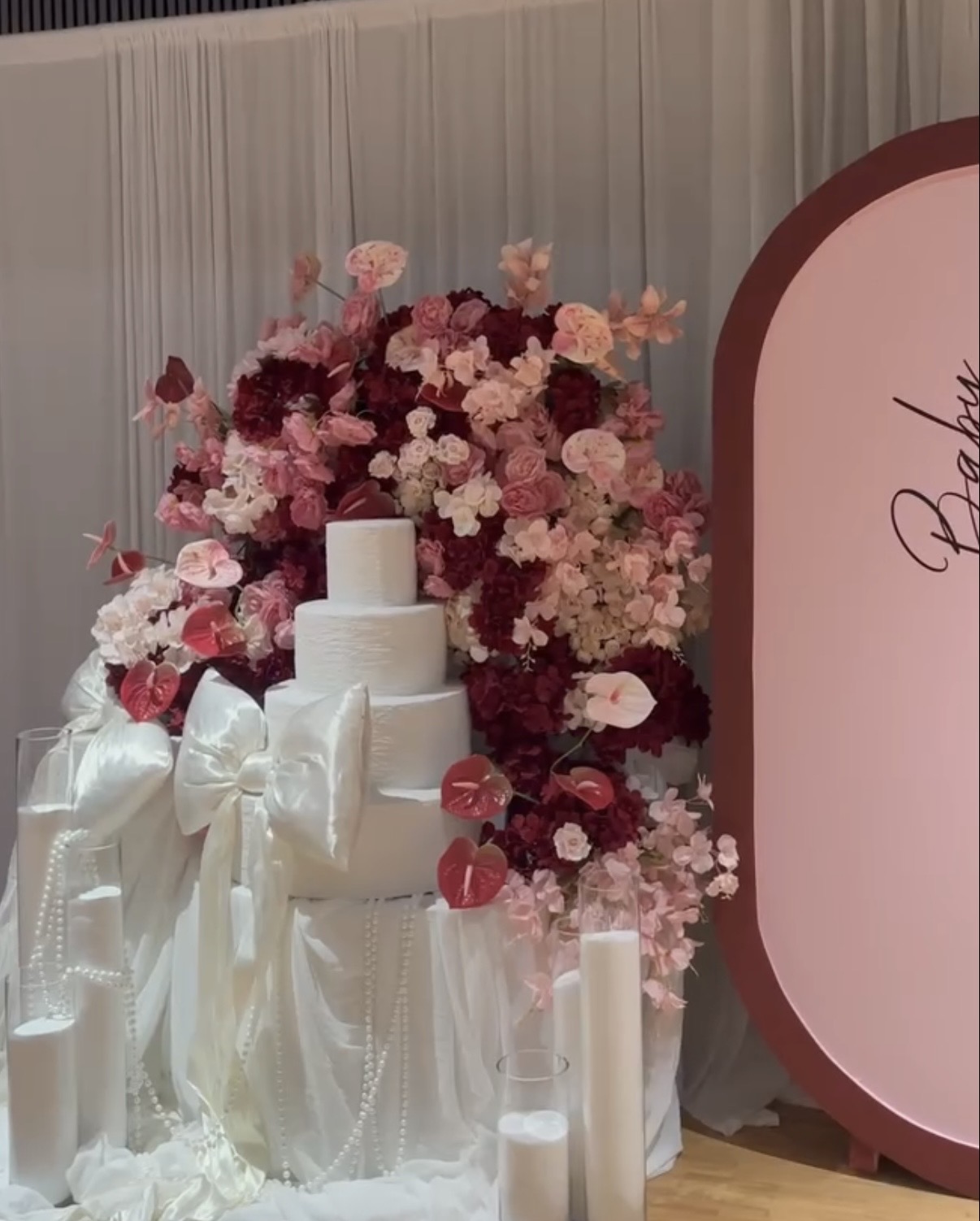 Tårta framför blomstervägg i rosa och bourgogne